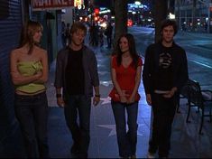 four young people walking down the street at night in front of a star on the hollywood walk of fame