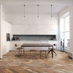 a dining room table and chairs in front of an open kitchen with white walls, wood flooring and large windows