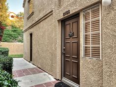 a brown door is on the side of a tan building