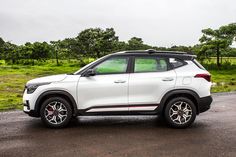 a white car parked in a parking lot next to some green grass and trees on a cloudy day