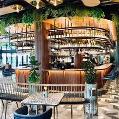 the bar is decorated with greenery and hanging lights, along with wooden tables and chairs