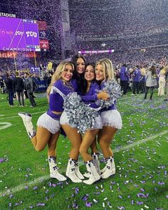 three cheerleaders hugging on the sidelines at a football game with confetti thrown in the air