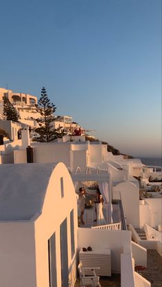 white buildings on the side of a hill with blue sky and ocean in the background