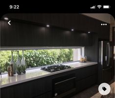 a modern kitchen with black cabinets and white counter tops, along with an outdoor view