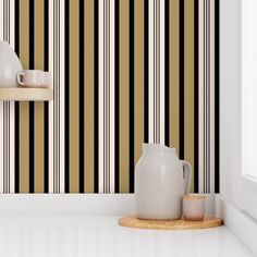 a white vase sitting next to a black and gold striped wall