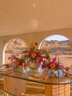 a dining room table with flowers on it in front of an open desert view window