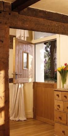 a room with wooden floors and white walls has a vase on top of the dresser