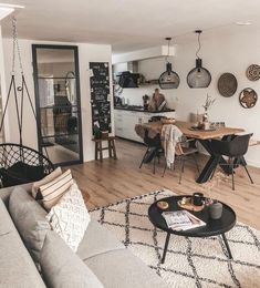 a living room filled with furniture next to a kitchen and dining room table on top of a hard wood floor