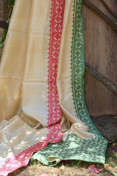 an old blanket laying on the ground next to a wooden fence with flowers in it