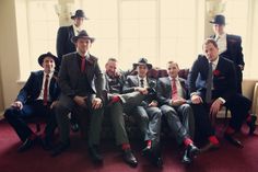 a group of men sitting next to each other in suits and ties on a red carpeted floor