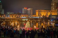 a large group of people standing around a christmas tree in the middle of a city