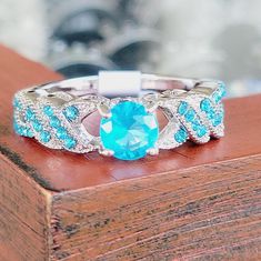 a ring with blue and white stones is sitting on top of a wooden box