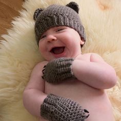 a smiling baby wearing knitted mittens and gloves