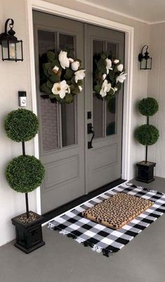 the front door is decorated with topiary balls and potted plants for an elegant touch