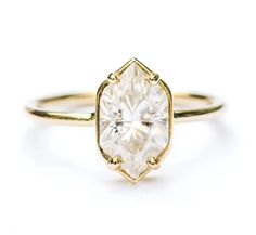 a yellow gold ring with an oval cut diamond in the center, on a white background