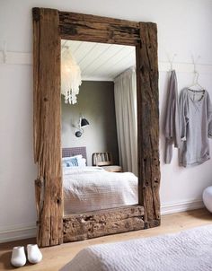 a mirror sitting on top of a wooden floor next to a bed