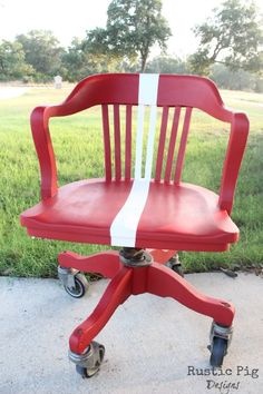 a red and white chair sitting on top of a cement floor in front of grass