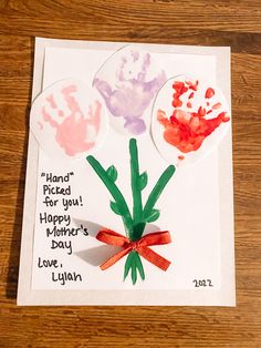 a handprinted card with three flowers and the words happy mother's day written on it