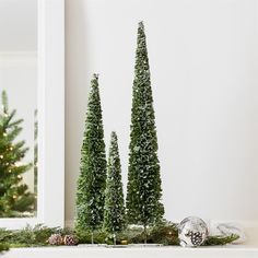 three small christmas trees in front of a mirror