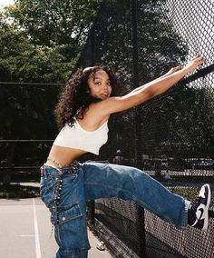 a woman in white shirt and jeans holding a tennis racquet