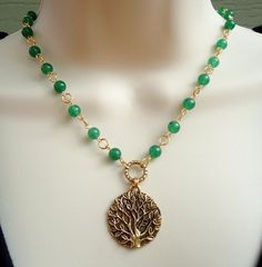 A beautiful sculpted gold tree of life pendant hangs from a hand made chain consist of green jade gemstones, all plated in 24 karat gold. This striking necklace is finished with a spring ring clasp. The necklace measures 16 inch in length, with 2 inches extension. Pendant measures 1.5 inch. Also available in sterling silver plate. Available in many color stones chain. Gold Jade Necklace With Gemstone Beads, Gold Aventurine Beaded Necklaces, Gold Aventurine Necklace With Gemstone, Gold Aventurine Gemstone Necklace, Handmade Yellow Gold Jade Necklaces, Handmade Yellow Gold Jade Necklace, Elegant Wire Wrapped Jewelry For Meditation, Gold Necklace With Green Onyx Gemstone Beads, Bohemian Gold Jade Jewelry