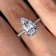 a woman's hand with a diamond ring on top of her finger and an engagement band