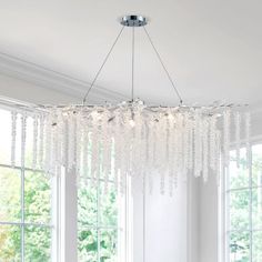 a chandelier hanging from the ceiling in a living room with white walls and windows