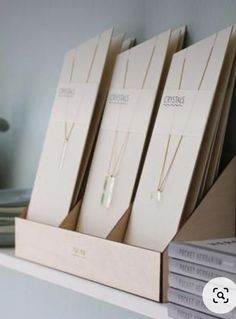 three necklaces are sitting in a wooden box on a shelf next to some books