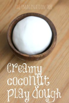 a wooden bowl filled with creamy coconut play dough on top of a wooden table