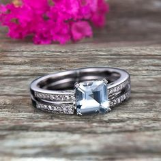 an engagement ring and wedding band set on a wooden table with flowers in the background