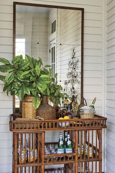 a mirror sitting on top of a wooden shelf next to a table filled with drinks