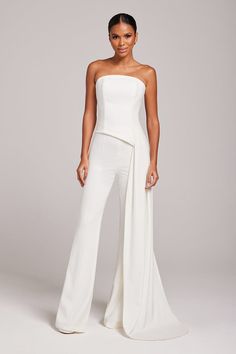 DESCRIPTION & FEATURES The stunning FAYE White top is a modern bridal boned top with floor-length drape. This top is perfect for dinner dates or engagement shoots, make it elegant and formal with our CHARLOTTE White Pants, CAMILLE White Pants or pair with the matching FAYE White Skirt. - Boned top - Crafted from our exclusive crepe - Floor length drape to side- Outer: 94% Polyester 6% Elastane Lining: 94% Polyester 6% Elastane SIZE & FIT INFORMATION - Fits true to size, take your normal size - M Pageant Interview Outfit, White Bra Top, Jumpsuits Womens Fashion, Nadine Merabi, Formal Fashion Women, Pant Suits, White Trousers, Elegant Sophisticated, White Bras