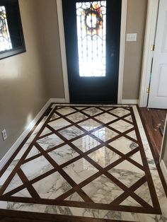 an entryway with marble flooring and stained glass window in the door way to another room