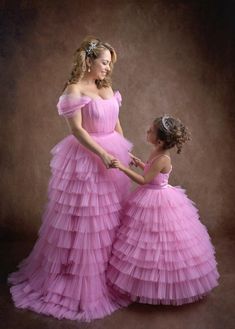 mother and daughter in pink dresses posing for the camera with their hands on each other