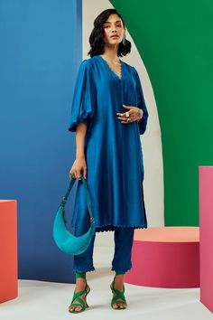 Royal blue straight kurta with scallop trim on the neckline and exaggerated puff sleeves. Comes with straight pants.
Components:2

Neckline:V neck
Sleeve Type:Puff Sleeves
Fabric:Silk
Color:Blue
Other Details:
Pleated back
Pant with scalloped trim at the hems
Note: Bag carried by the model is not for sale
Occasion:Work
Disclaimer: Product colour may slightly vary due to photographic lighting sources and  there can be slight difference in motif print placement due to running print fabric. - Aza F Ridhi Mehra, Silk Kurta, Scallop Trim, Straight Kurta, Pakistani Dress Design, Scalloped Trim, Kurta With Pants, Print Placement, Fabric Silk