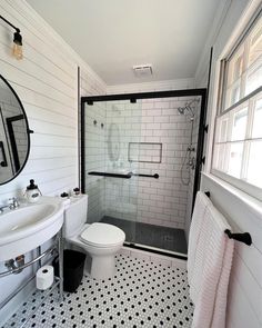 a bathroom with black and white tile flooring and walls, along with a walk in shower