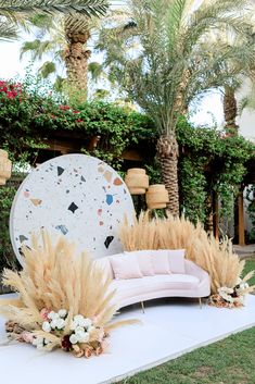 a couch sitting on top of a lush green field next to tall grass and palm trees