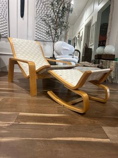 a pair of lounge chairs sitting on top of a hard wood floor next to a plant