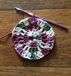 a crocheted dishcloth with a purple and white circle on top of it