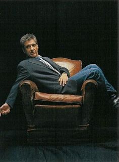 a man in a suit and tie sitting on a chair