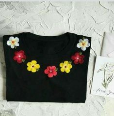 a black t - shirt with colorful flowers on it and a card next to it