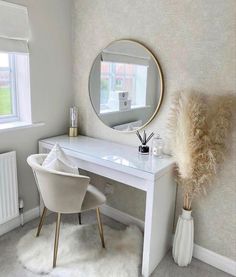 a white desk with a mirror, chair and vase on it in front of a window