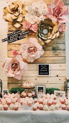 a table topped with cupcakes covered in frosting next to a wooden wall