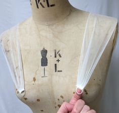 a mannequin's torso with plastic wrapped around the neck and hands pointing at it