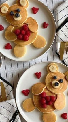 two white plates topped with pancakes covered in fruit and teddy bear shaped toppings,