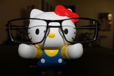 a hello kitty figurine with glasses on it's head sitting on a table