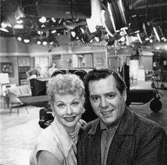 an old black and white photo of a man and woman posing for the camera in a large room