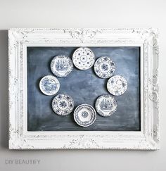 a white frame with blue and white plates arranged in a circle on the wall above it