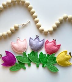 four felt flowers are sitting on a bead necklace