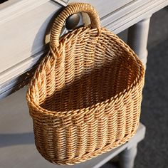 a wicker basket hanging from the side of a white bench with handles on it